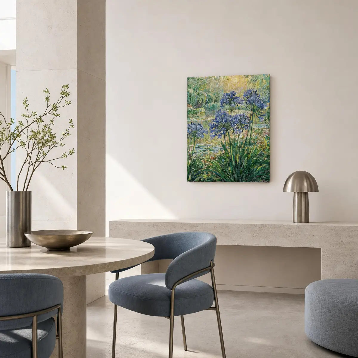 A framed floral wall art print hangs on a light beige wall in a modern dining room setting with blue-gray chairs, a stone table, and a metallic lamp.