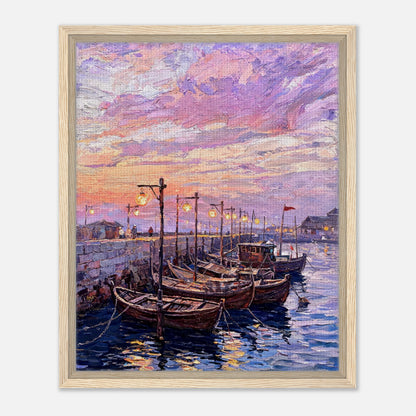 A framed canvas print of an impressionist painting depicting wooden boats moored in a harbor under a pink, purple, and orange sunset sky.
