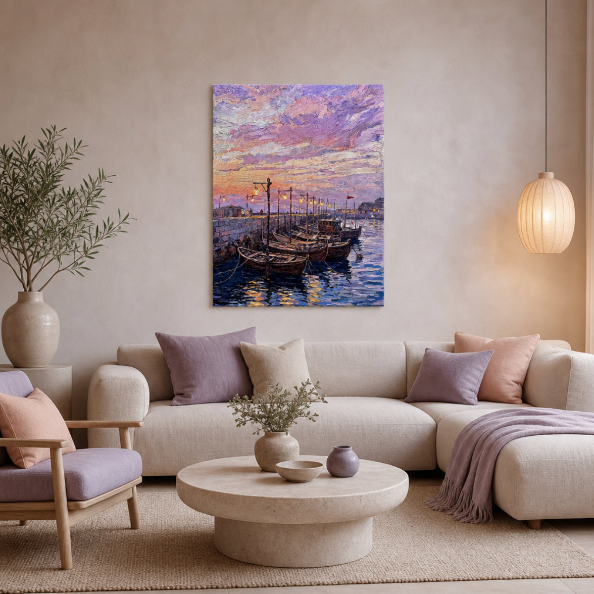 A vertical canvas painting of traditional boats on water at sunset, displayed on a beige wall in a modern, cozy living room setting with a sofa, armchair, and pendant light.