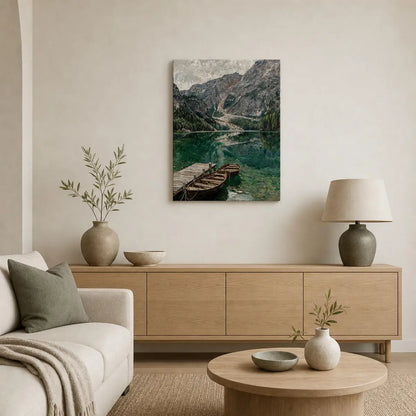 A framed landscape art print depicting a mountain lake with wooden boats, displayed on a beige wall above a light wood console table in a modern, neutral-toned living room.