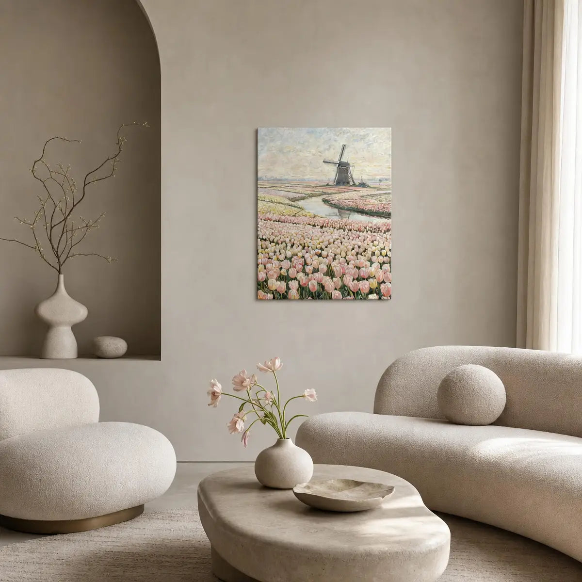 A vertical canvas art print depicting a Dutch windmill and pink tulip fields, styled on a beige wall in a modern, minimalist living room with neutral-toned furniture.