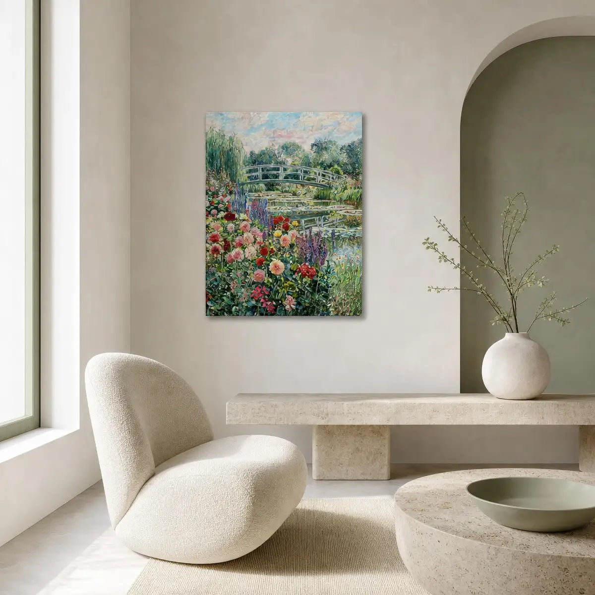 A framed-style vertical canvas print of a Monet-style garden landscape with flowers, bridges, and water, displayed on a beige wall in a modern minimalist living room with a curved cream chair, stone bench, and vase.