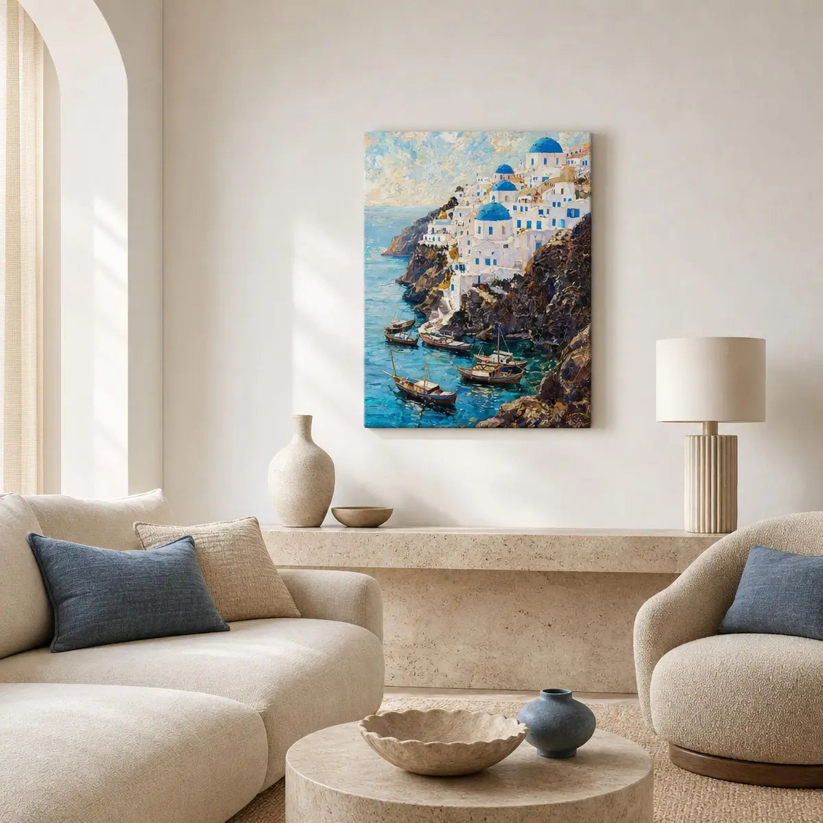 A vertical canvas print of a Santorini coastal scene with white buildings, blue domes, and turquoise water, displayed on a cream wall in a modern, neutral-toned living room setting.