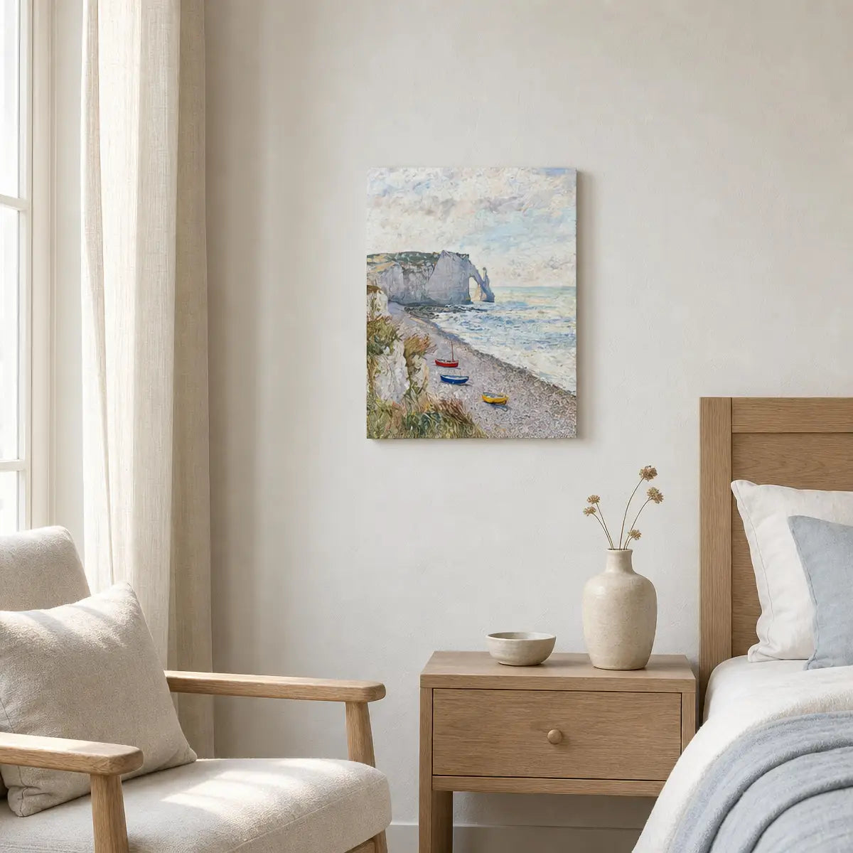 A canvas wall art print depicting a coastal beach scene with cliffs, boats, and a cloudy sky, styled in a modern bedroom setting above a wooden nightstand and bed.