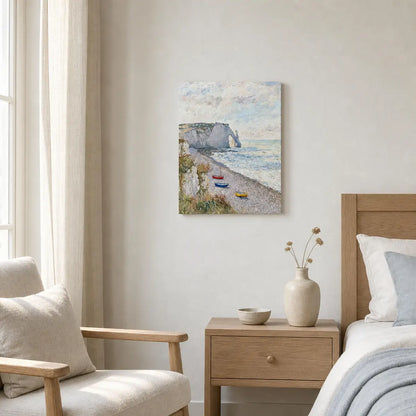 A canvas wall art print depicting a coastal beach scene with cliffs, boats, and a cloudy sky, styled in a modern bedroom setting above a wooden nightstand and bed.